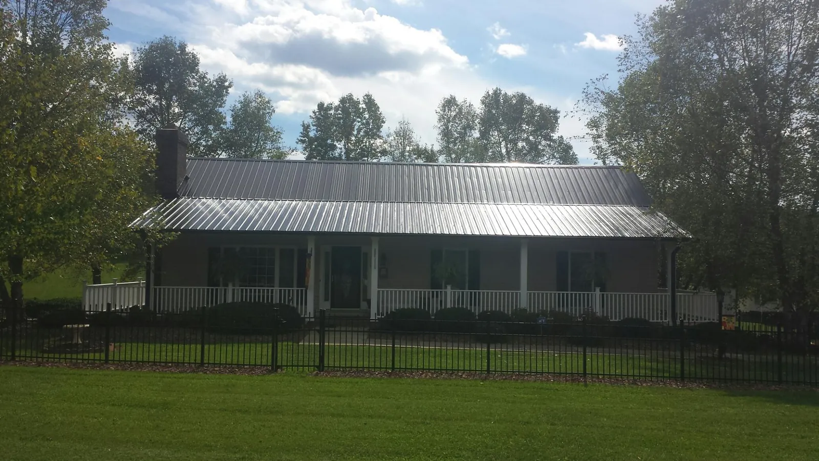 Gray metal roof on a brick ranch with a full width front porch — Gutter Guard Installation work by our crew in Silsbee