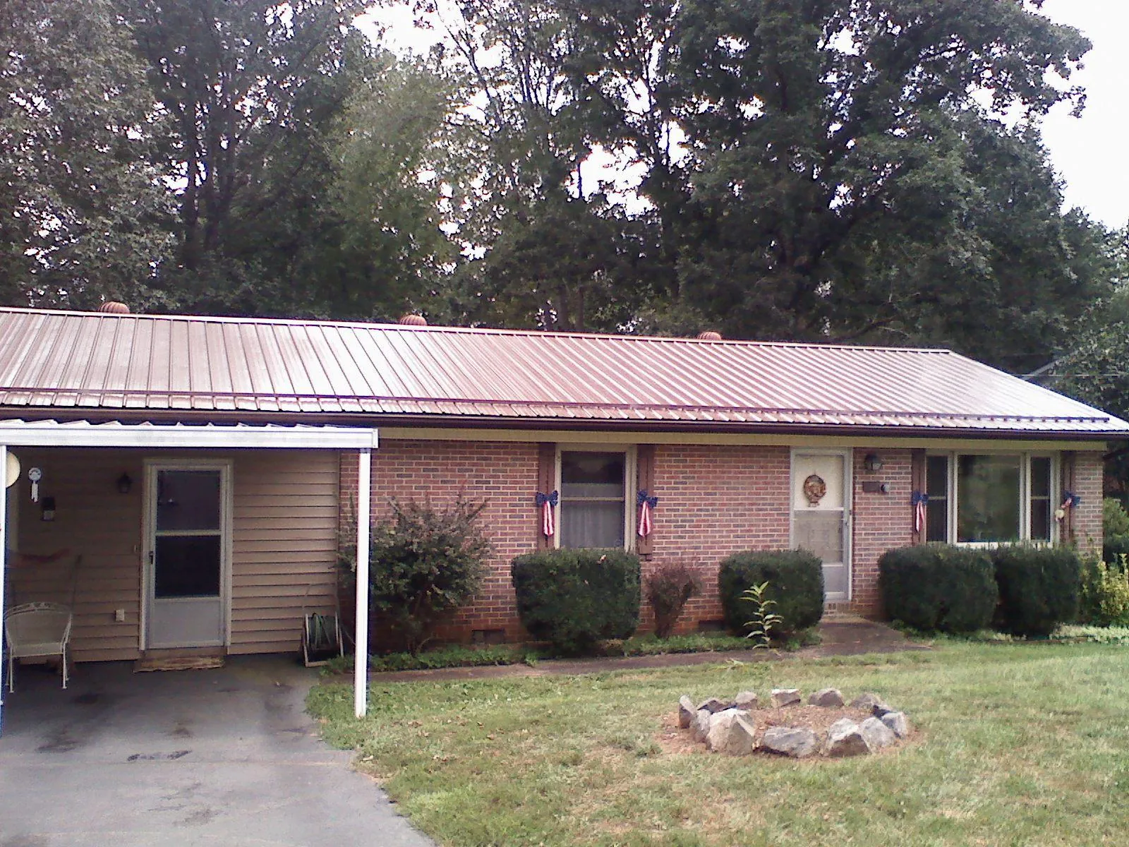Bronze metal roof and carport on a brick ranch home — Roof Repair work by our crew in Silsbee