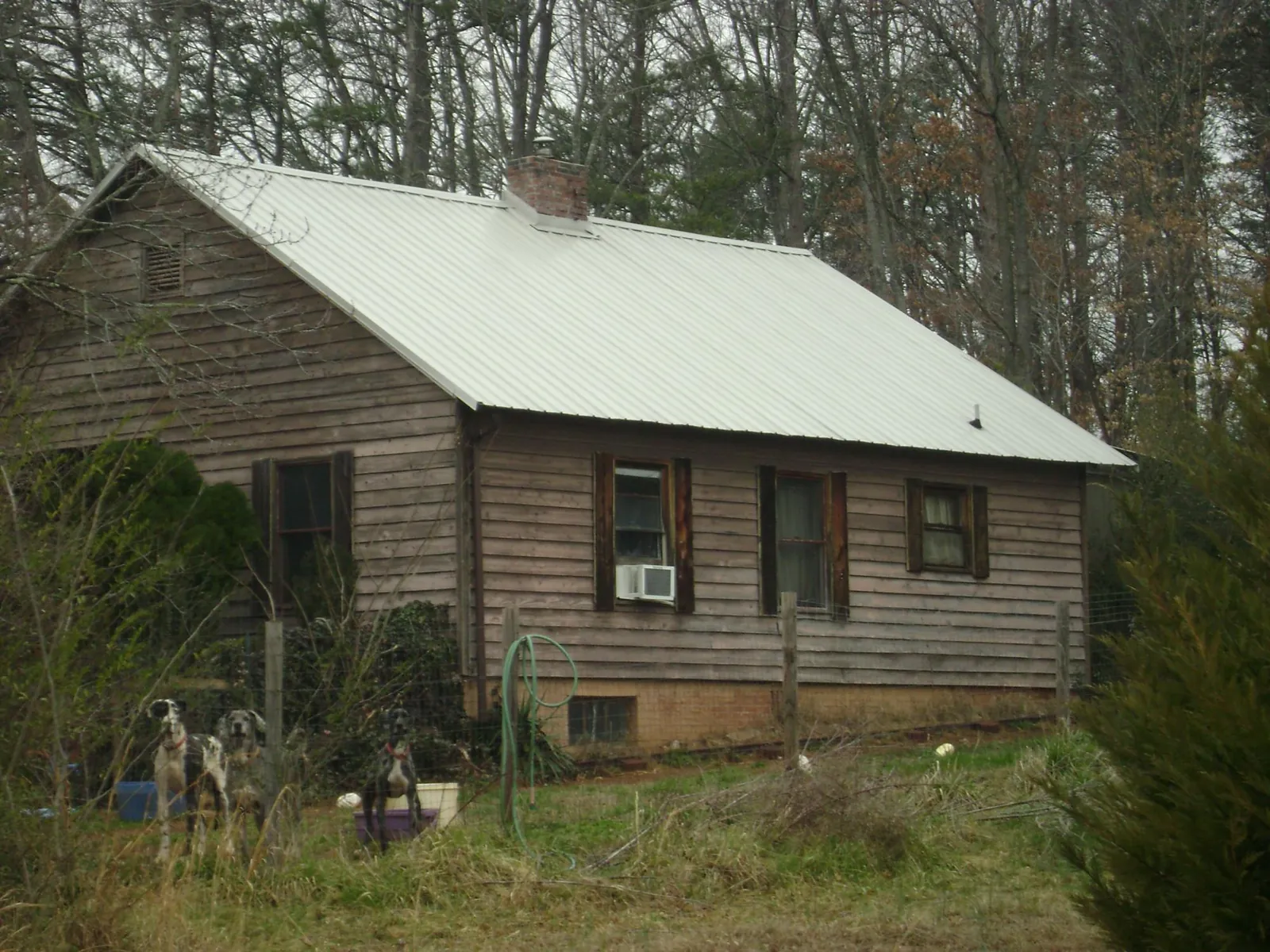 White metal roof on an old wood sided farmhouse, from a Metal Roof Installation job in Silsbee