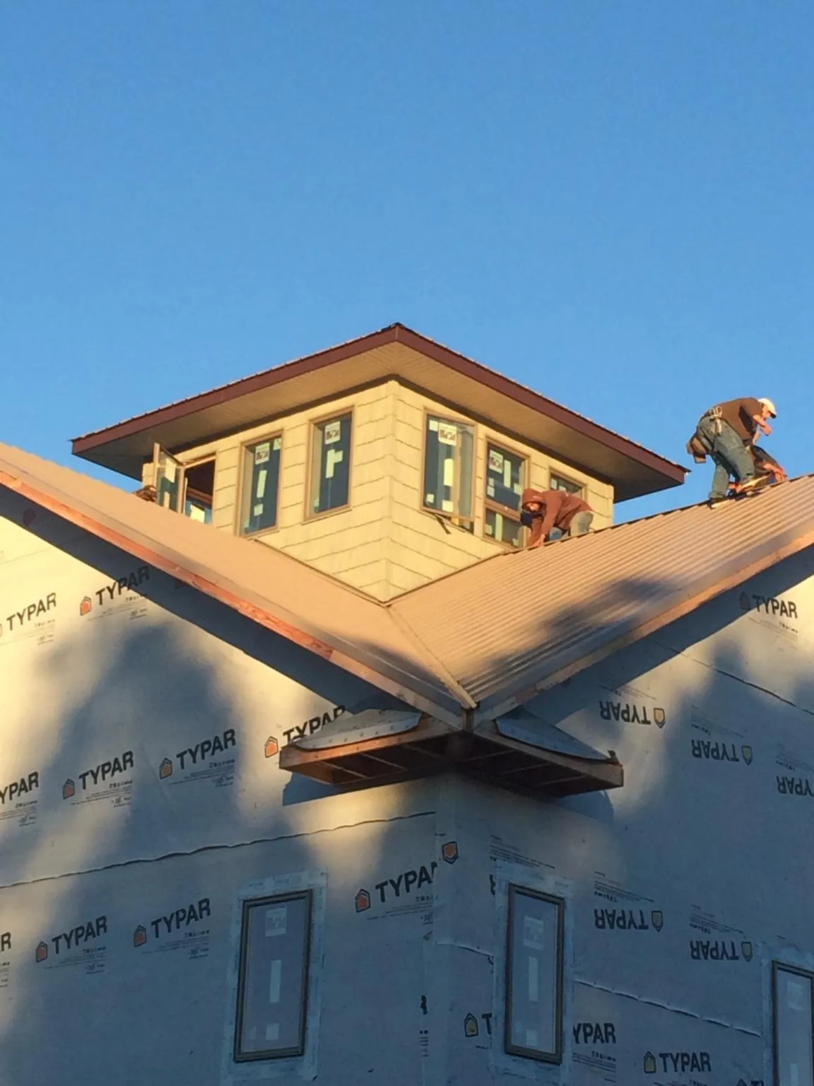 Roofers working around a rooftop cupola on a new metal roof at sunset — Roof Waterproofing in Silsbee by Roofing Brothers